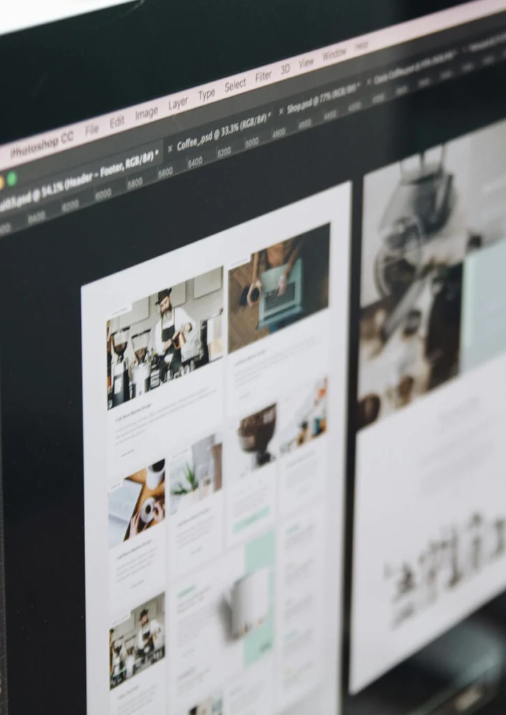 Nahaufnahme eines Computerbildschirms mit der Oberfläche einer Designsoftware. Der Bildschirm zeigt zwei Bereiche eines Webdesignprojekts mit Bildern und Textlayouts, das mit Photoshop CC erstellt wurde. Das Design zeigt Kaffee-Elemente und präsentiert innovative Weblösungen.